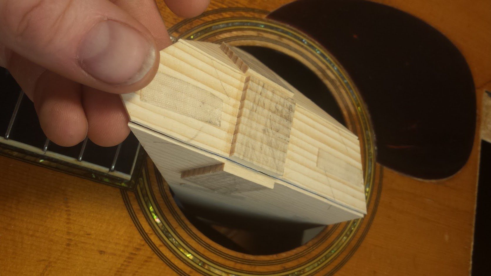 The "top" or the non-show side is scored about halfway through the patch with a sharp blade The score lines are in the soft, spring growth grain. Next, it is broken along those score lines. This is to prevent a seam from showing inside the guitar once it is in place. Also, a break will help register all three pieces together cleanly inside.